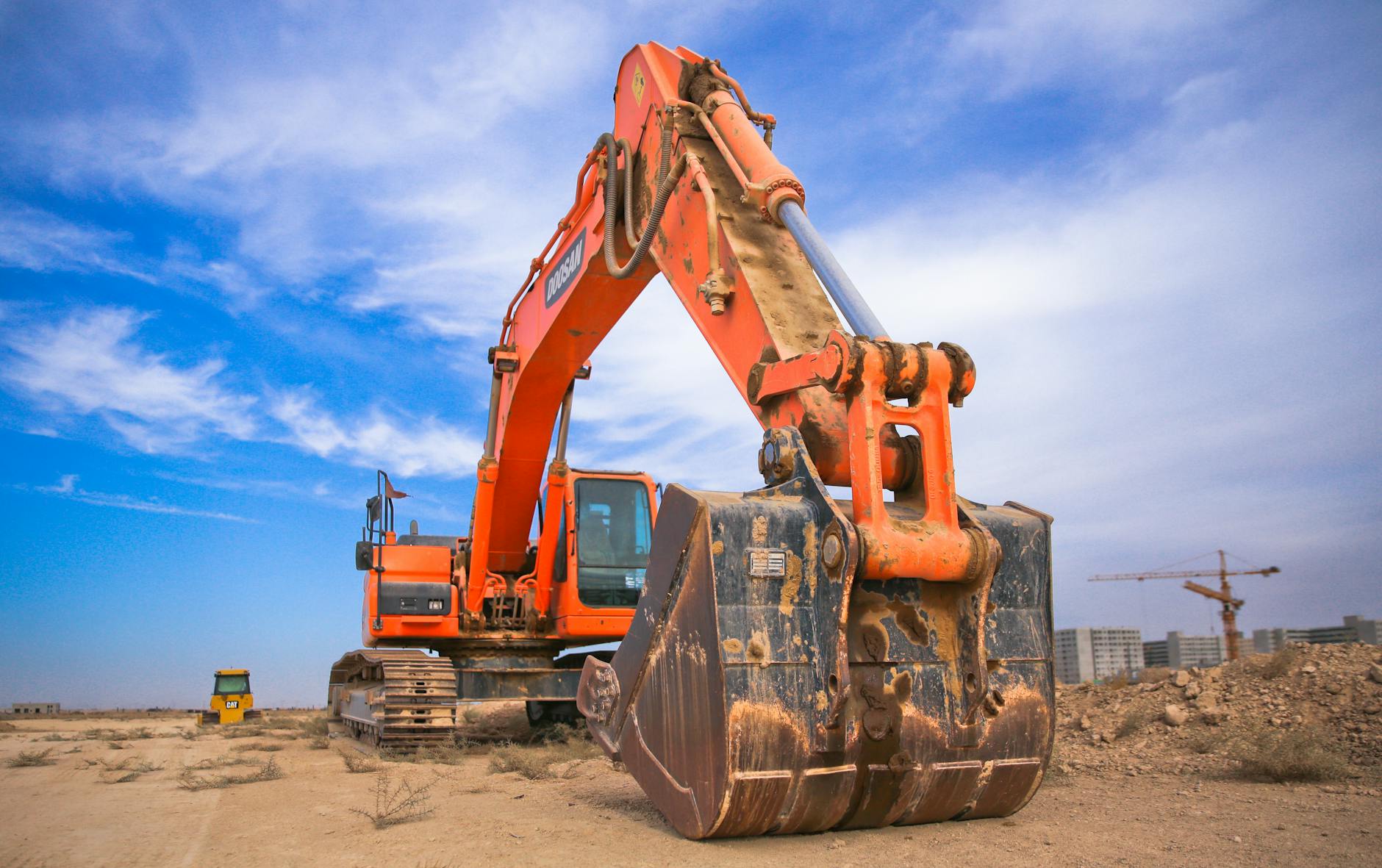 low angle photography of orange excavator under white clouds